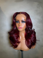 Mannequin head with burgundy wig on a neutral background