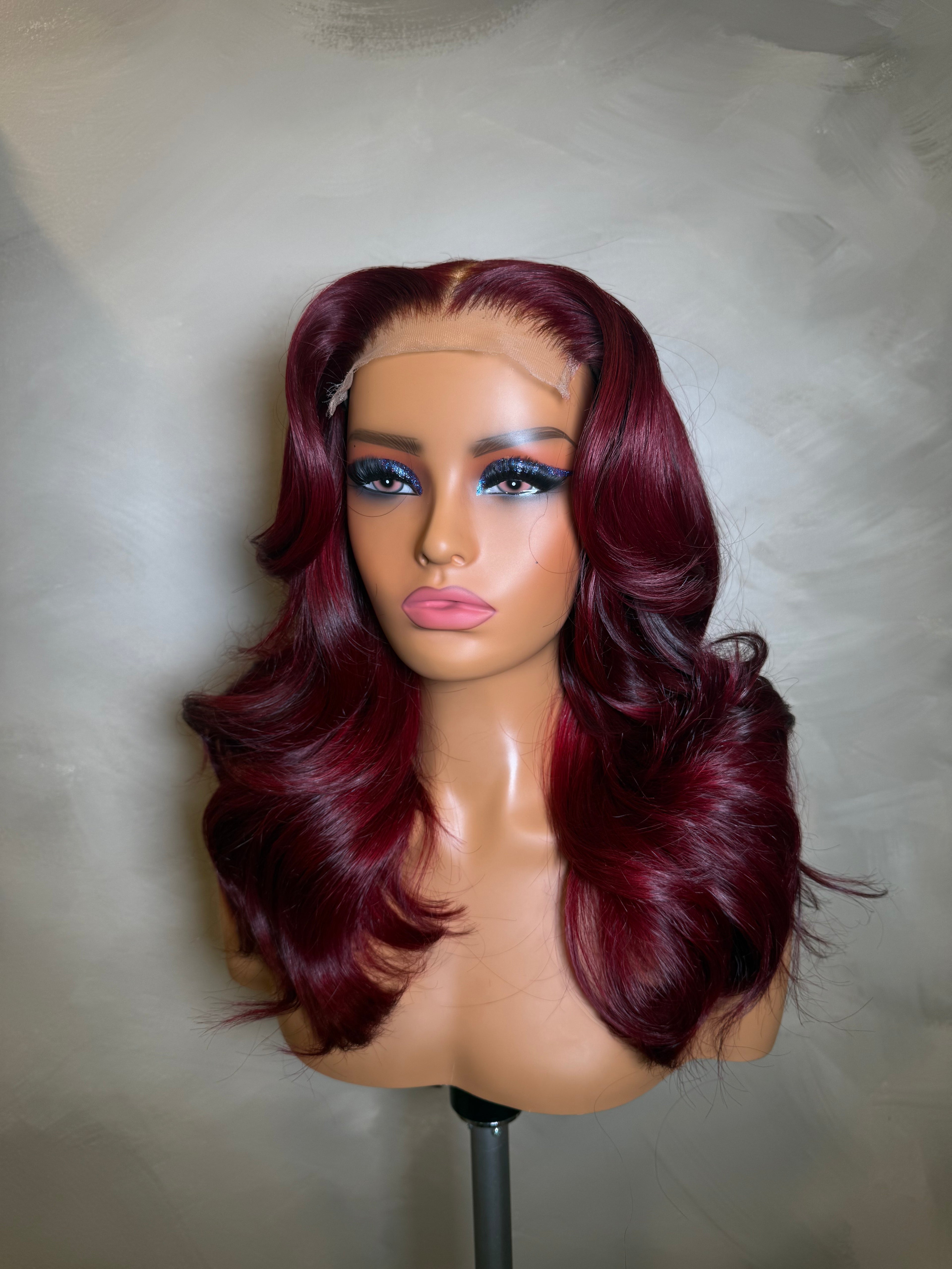 Mannequin head with burgundy wig on a neutral background