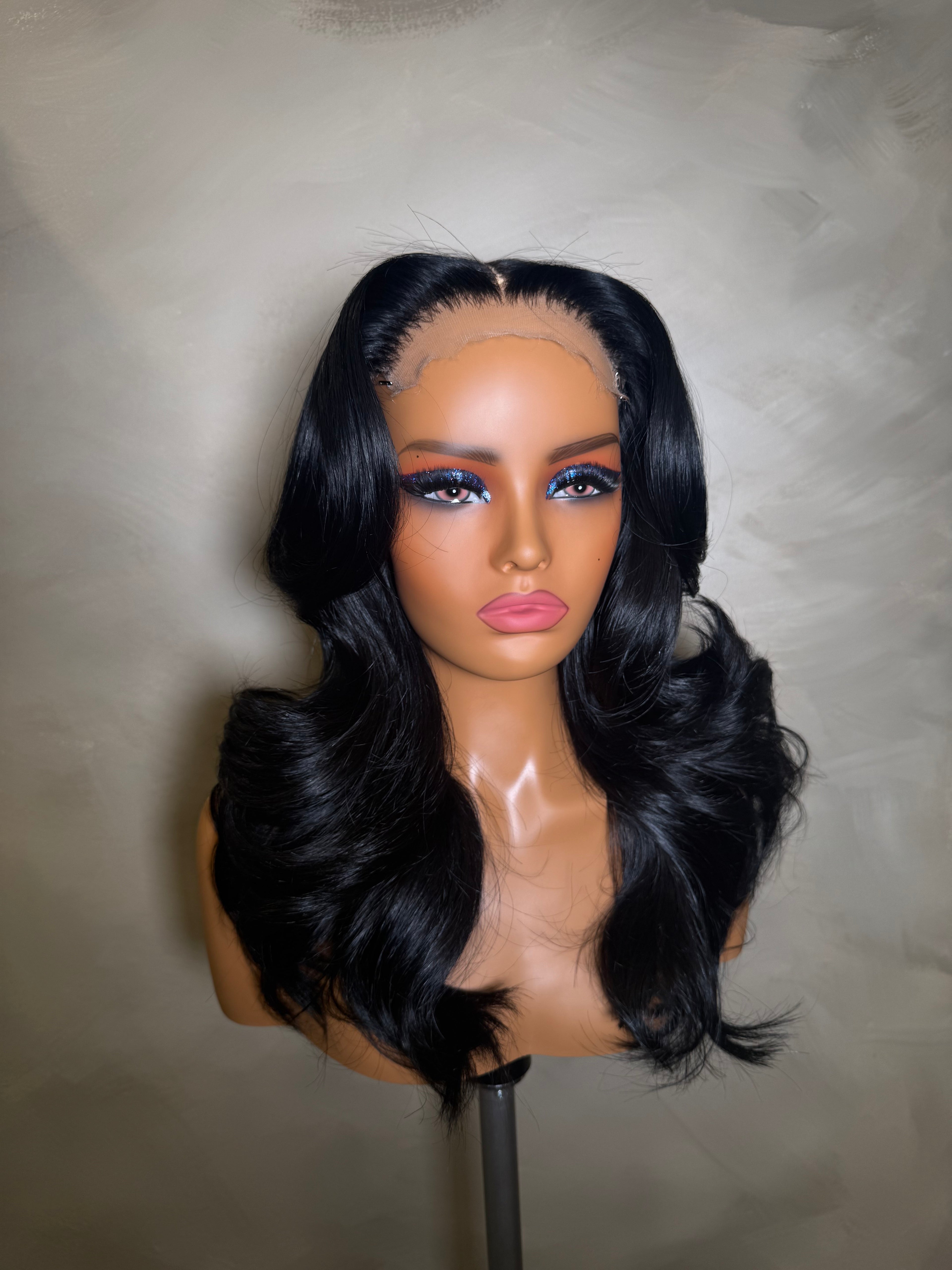 Black wig on a mannequin head against a neutral background